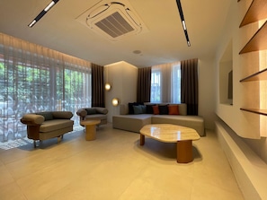 A modern living room with a sofa, armchairs, a coffee table, and a fireplace.