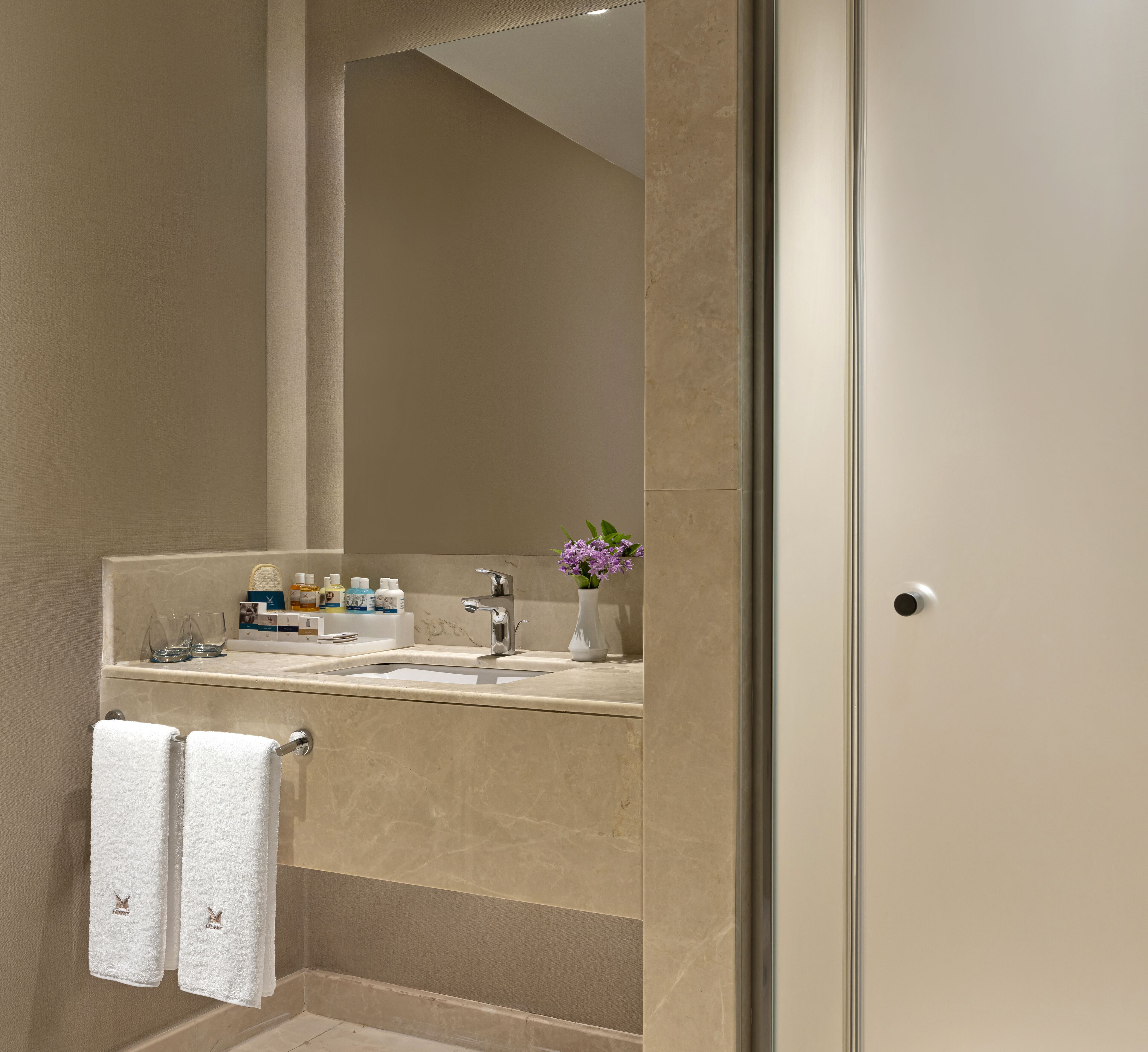 Un bany modern amb un mirall gran, un lavabo i un suport per tovalloles.