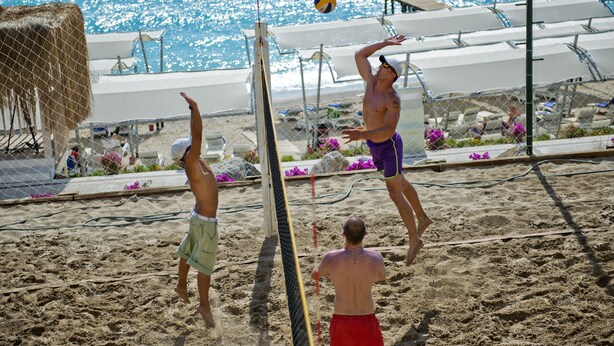 Un match de volleyball de plage avec un filet et des joueurs en shorts.