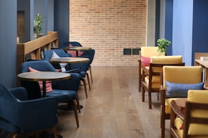 A cafe with wooden tables and chairs, a brick wall, and potted plants. - c-hotels Diplomat (Florence)