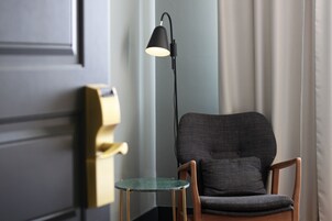 A room with a chair, a small table, a floor lamp, and a door.