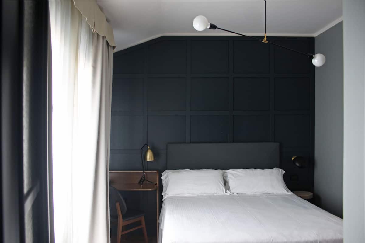 A bedroom with a bed, a desk, a chair, and two bedside lamps.