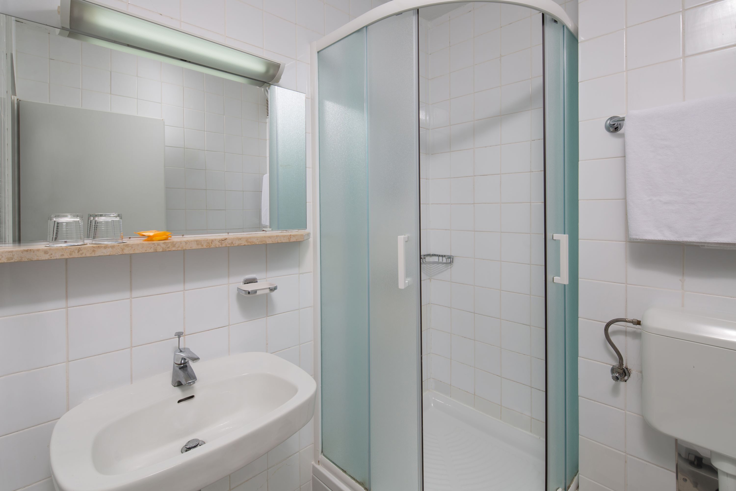 A bathroom with a glass-enclosed shower, a sink, and a mirror.