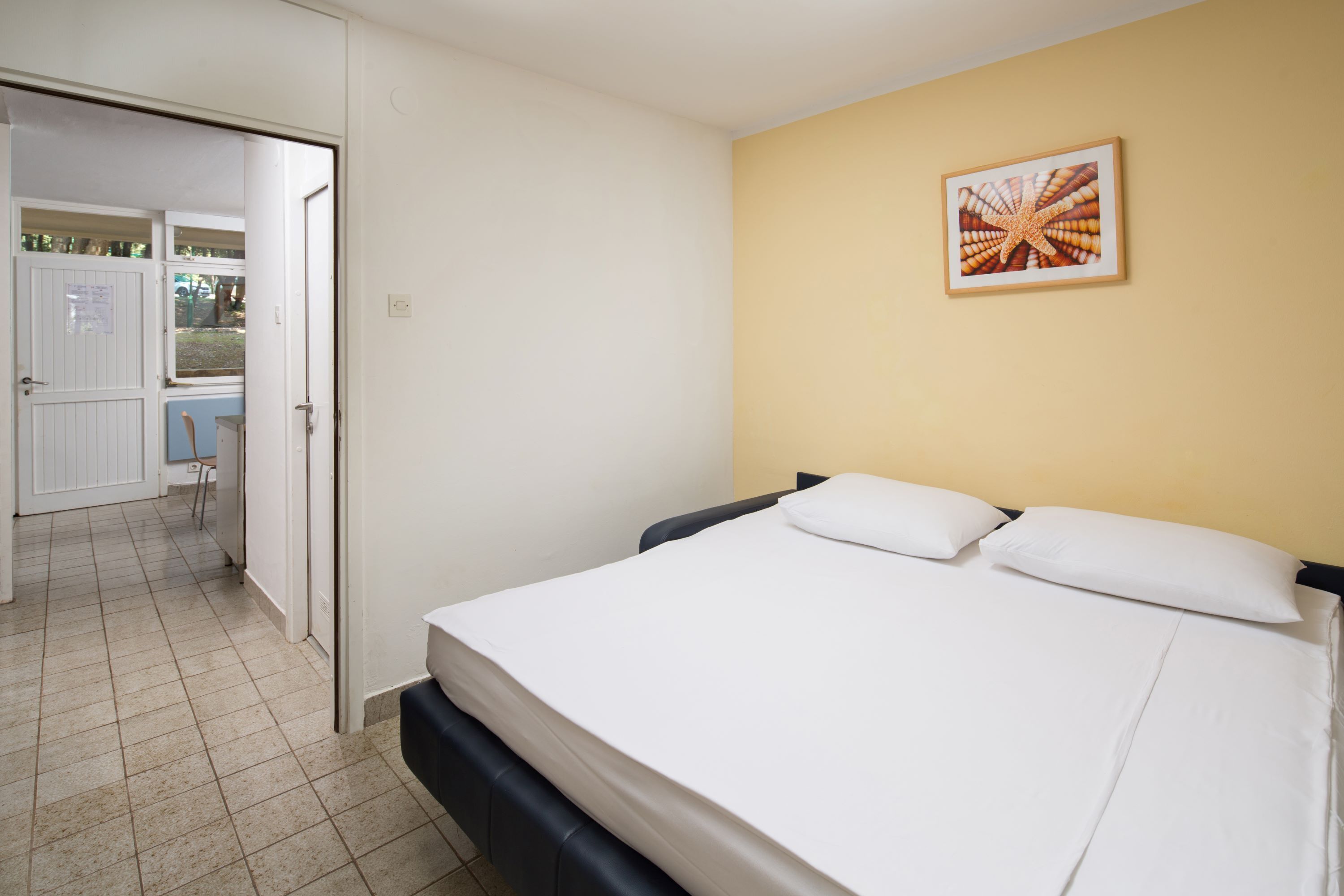 Une chambre d’hôtel avec un lit, une porte donnant sur un balcon et un tableau encadré au mur.