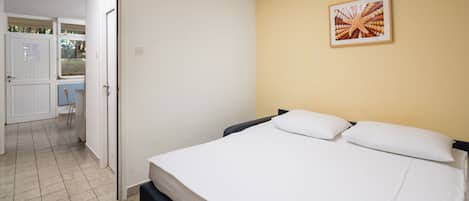 Une chambre d’hôtel avec un lit, une porte donnant sur un balcon et un tableau encadré au mur.