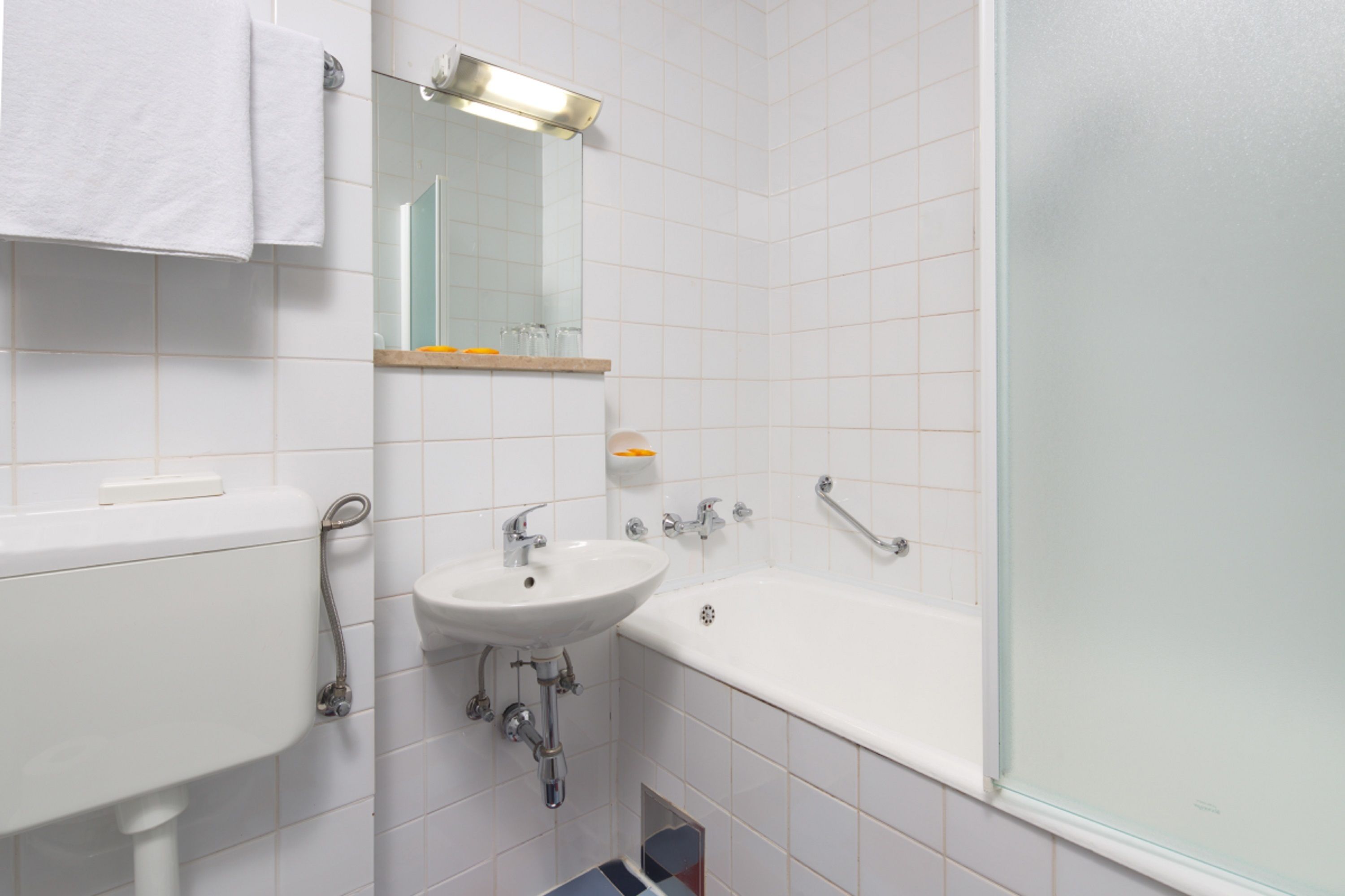 A bathroom with a sink, mirror, and bathtub.