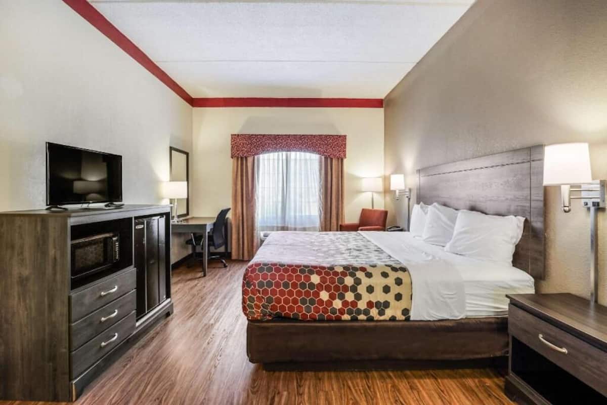A hotel room with a bed, a desk, a TV, and a wardrobe.