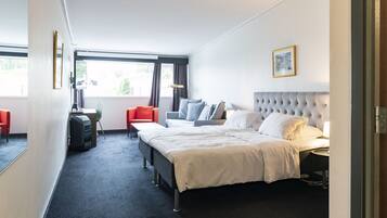 A hotel room with a bed, a desk, a chair, and a window.