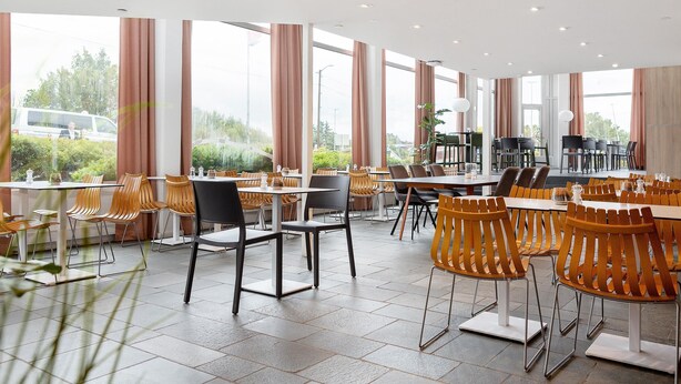 Un comedor espacioso con techos altos y ventanas amplias, que presenta muebles modernos y vistas al exterior.