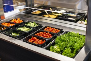Una barra de ensaladas con diversos vegetales y frutas.
