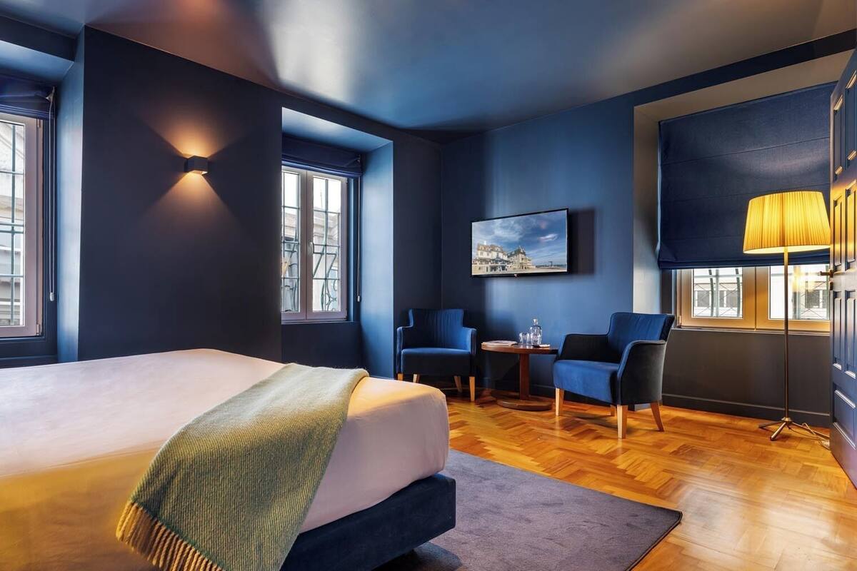 Habitación de hotel moderna con una cama grande, dos sillones, una mesita y un televisor.