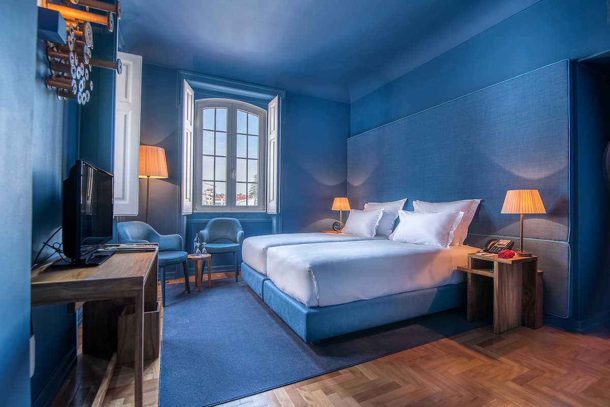 Habitación de hotel con una cama grande, un escritorio, una silla, un televisor y una ventana con vistas.