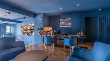 Una habitación moderna con paredes azules, una mesa de comedor de madera, sillas azules, un sofá y un escritorio con una computadora.