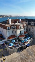 A hotel with multiple balconies overlooking a beach, featuring outdoor seating areas with umbrellas.