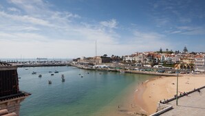 Un pueblo costero con playa de arena, barcos en el agua y edificios a lo largo de la orilla.