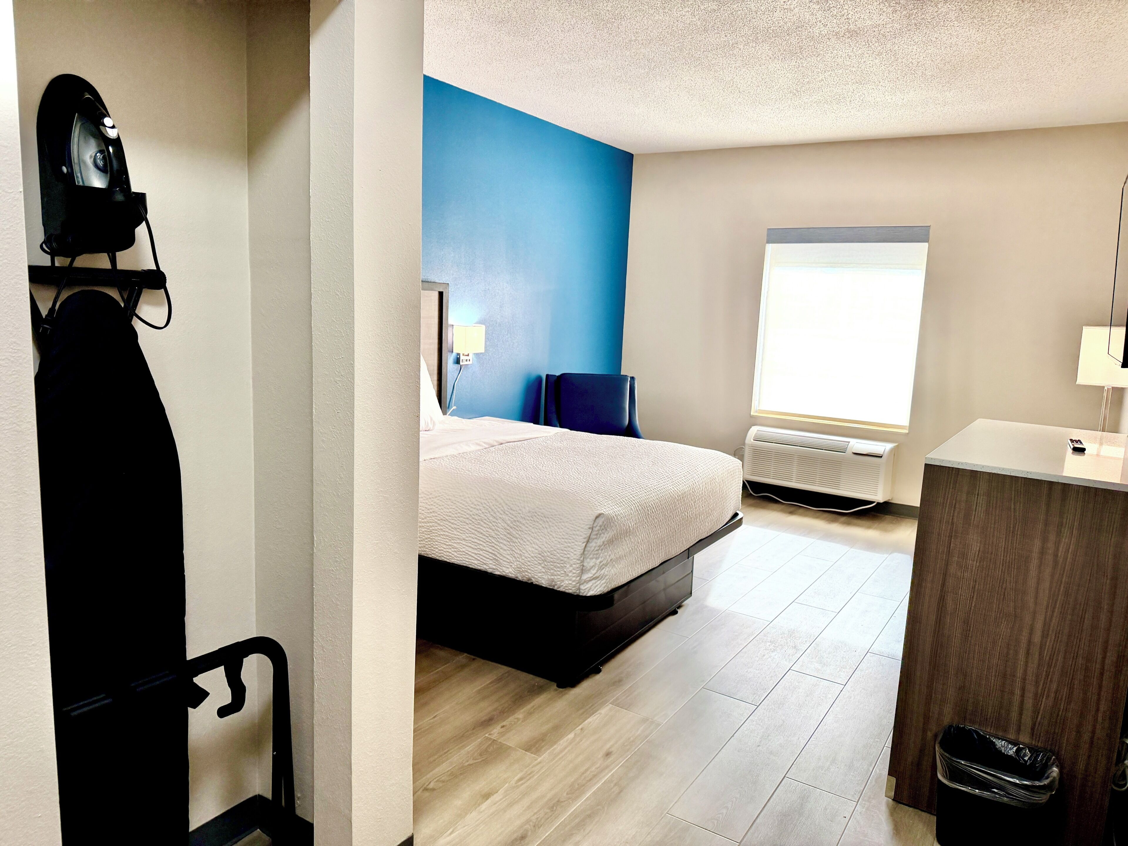 A bedroom with a bed, a desk, a chair, a radiator, and a window.