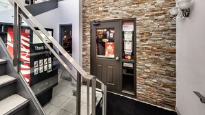 A modern interior with a stone wall, a glass elevator, and a door with a sign. - Isabella Hotel and Suites (Toronto)