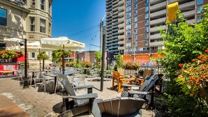 An outdoor seating area with Adirondack chairs and tables, surrounded by buildings and greenery. - Isabella Hotel and Suites (Toronto)