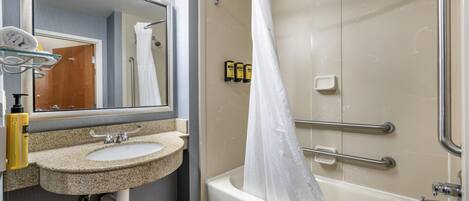 A bathroom with a sink, mirror, and bathtub.