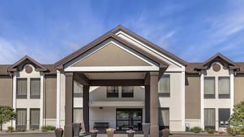 A hotel with a modern facade, a covered entrance, and a landscaped front yard.