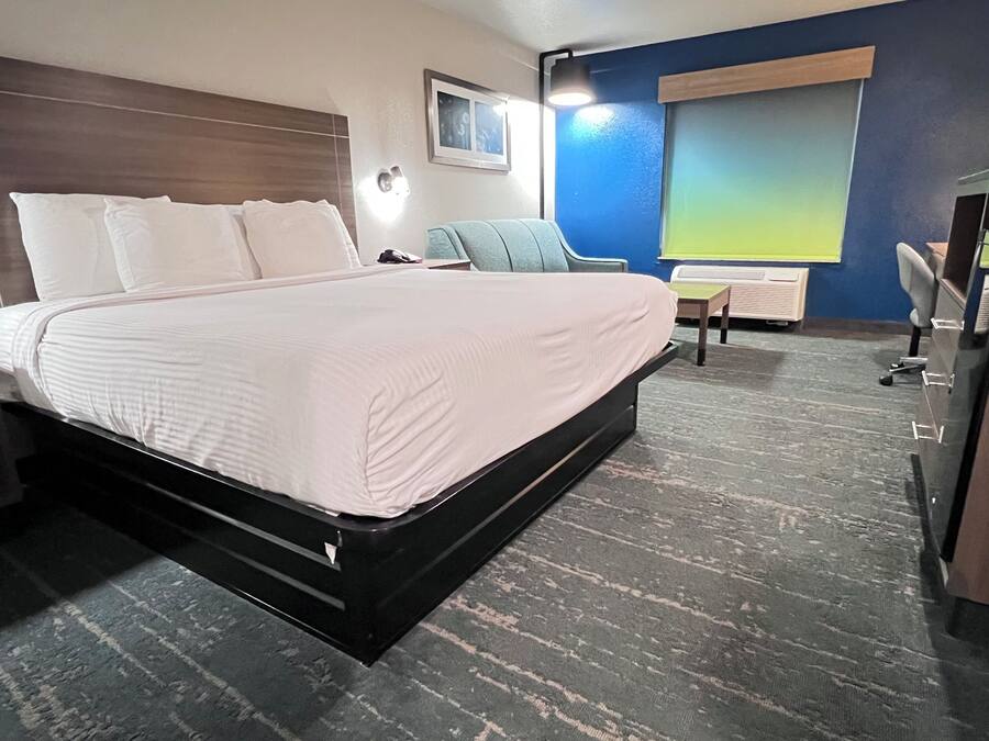 A hotel room with a large bed, bedside tables, a desk, and a chair.