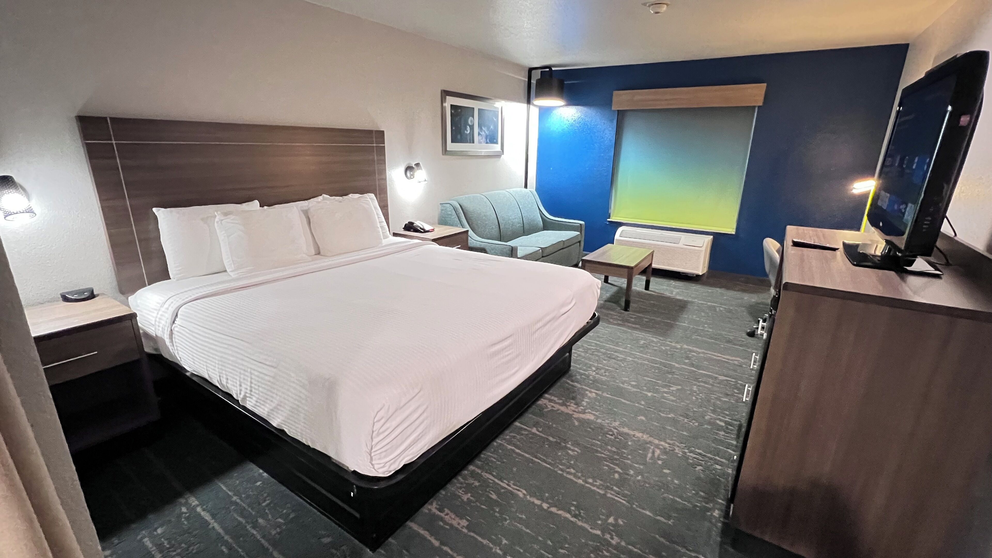 Ein Hotelzimmer mit einem großen Bett, einem Schreibtisch, einem Sessel, einem Fernseher und einem Fenster mit Blick.