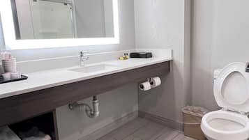 A modern bathroom with a large mirror, a sink, a toilet, and a shower area.