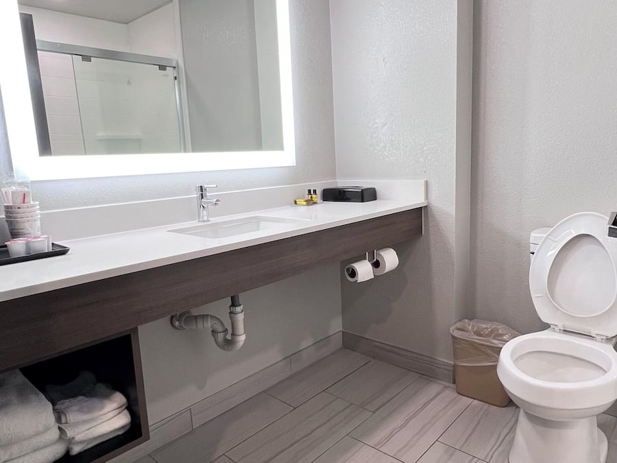 Ein modernes Badezimmer mit großem Spiegel, Waschbecken, Toilette und Duschbereich.