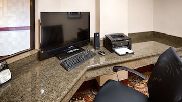 Um espaço de escritório em casa com um computador desktop, teclado, rato e impressora sobre uma bancada de granito.