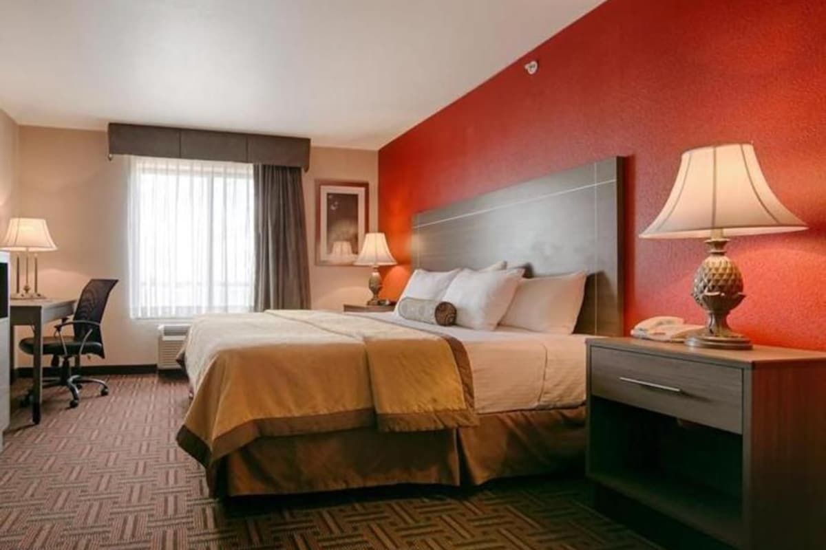 A hotel room with a bed, bedside tables, a desk, and a chair.