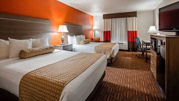 A hotel room with two beds, a television, a desk, and a chair.