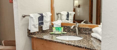 Un baño con lavamanos de encimera de granito, un espejo grande y un perchero para toallas.