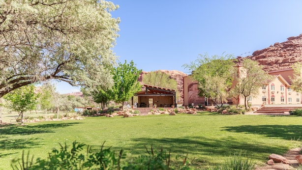 A hotel with a patio area, a covered outdoor seating space, and a view of red rock formations. - Aarchway Inn (Moab)