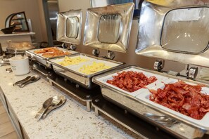 A buffet with various food options, including scrambled eggs, bacon, and other dishes.