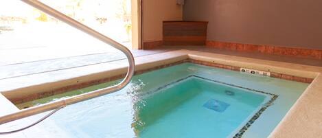 A swimming pool with a clear blue water feature, a metal ladder, and a tiled border.