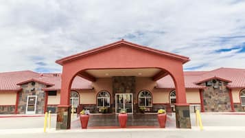 Stunning building with a central entrance and arched windows, set against a red-brick archway and red-tiled roof.