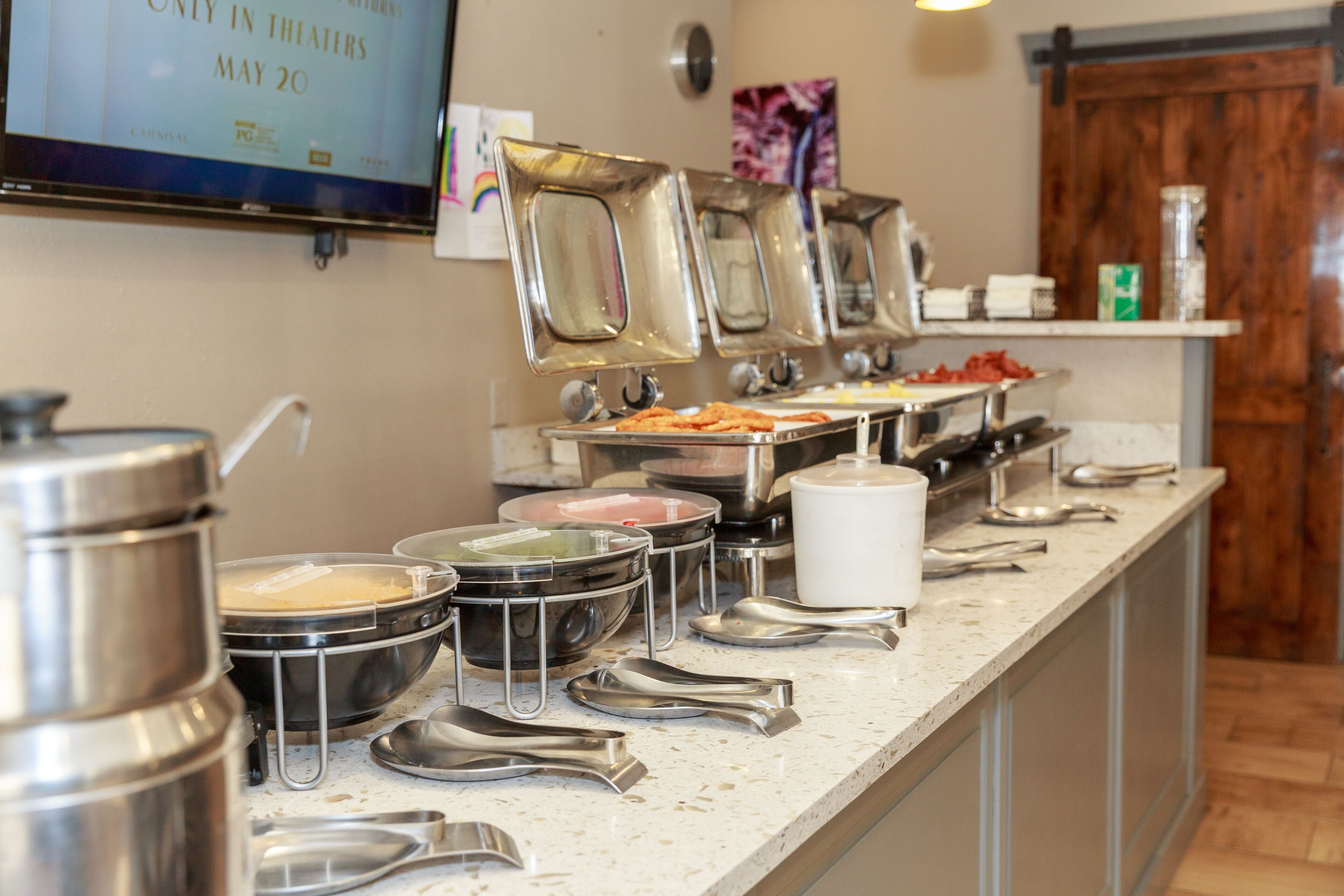 A buffet setup with various food containers and serving utensils.