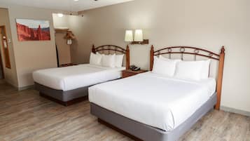Habitación de hotel con dos camas, un ventilador de techo, un cuadro en la pared y suelo de madera.
