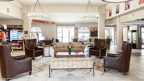 A spacious lobby with leather armchairs, a patterned bench, and a central sofa. A 'General Store' sign is visible in the background. - Aarchway Inn (Moab)