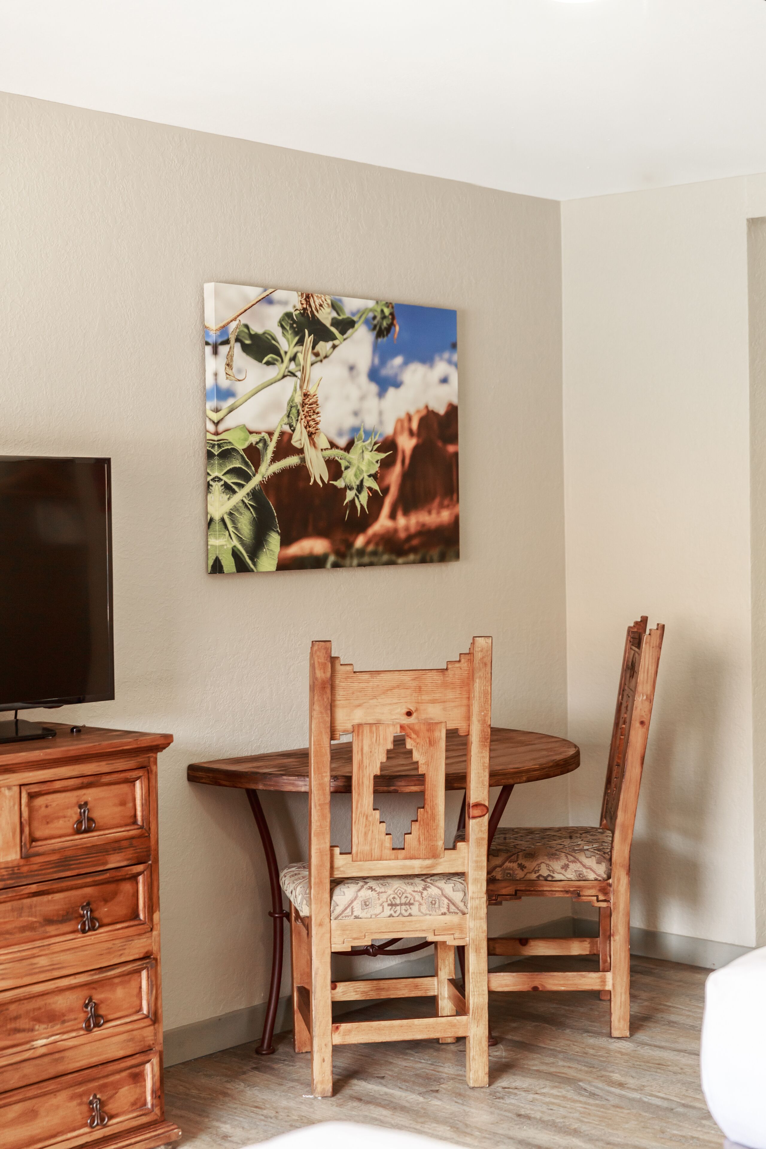 Un coin repas avec une table et des chaises en bois, un téléviseur et un tableau accroché au mur.