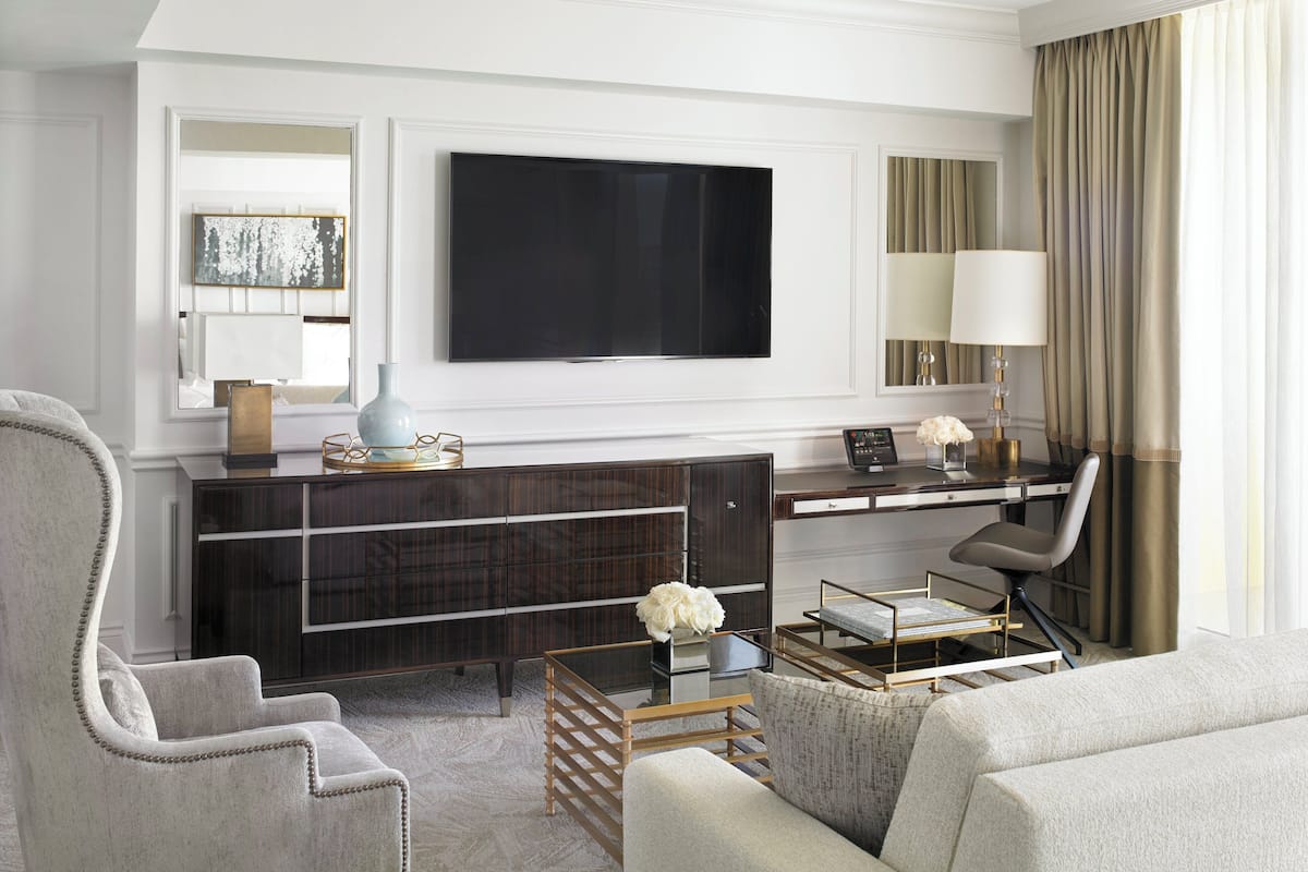 A modern living room with a large flat-screen TV, a sofa, a chair, a coffee table, and a desk with a lamp.