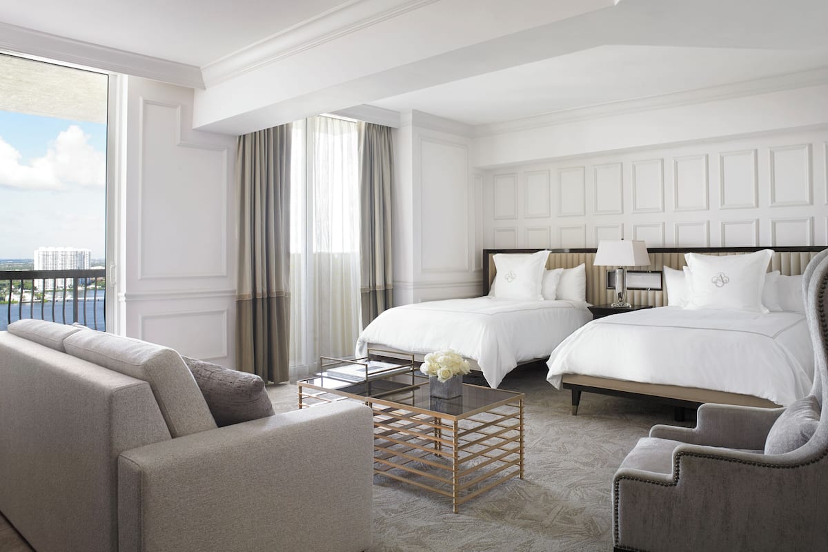 Habitación de hotel con dos camas, un sofá, una mesa de centro y vistas a la ciudad.