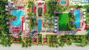 An aerial view of a resort with multiple swimming pools, sun loungers, and palm trees.