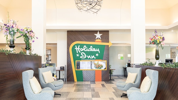 A Holiday Inn lobby with a reception desk, two armchairs, and a decorative sign. - Holiday Inn Effingham by IHG (Effingham)