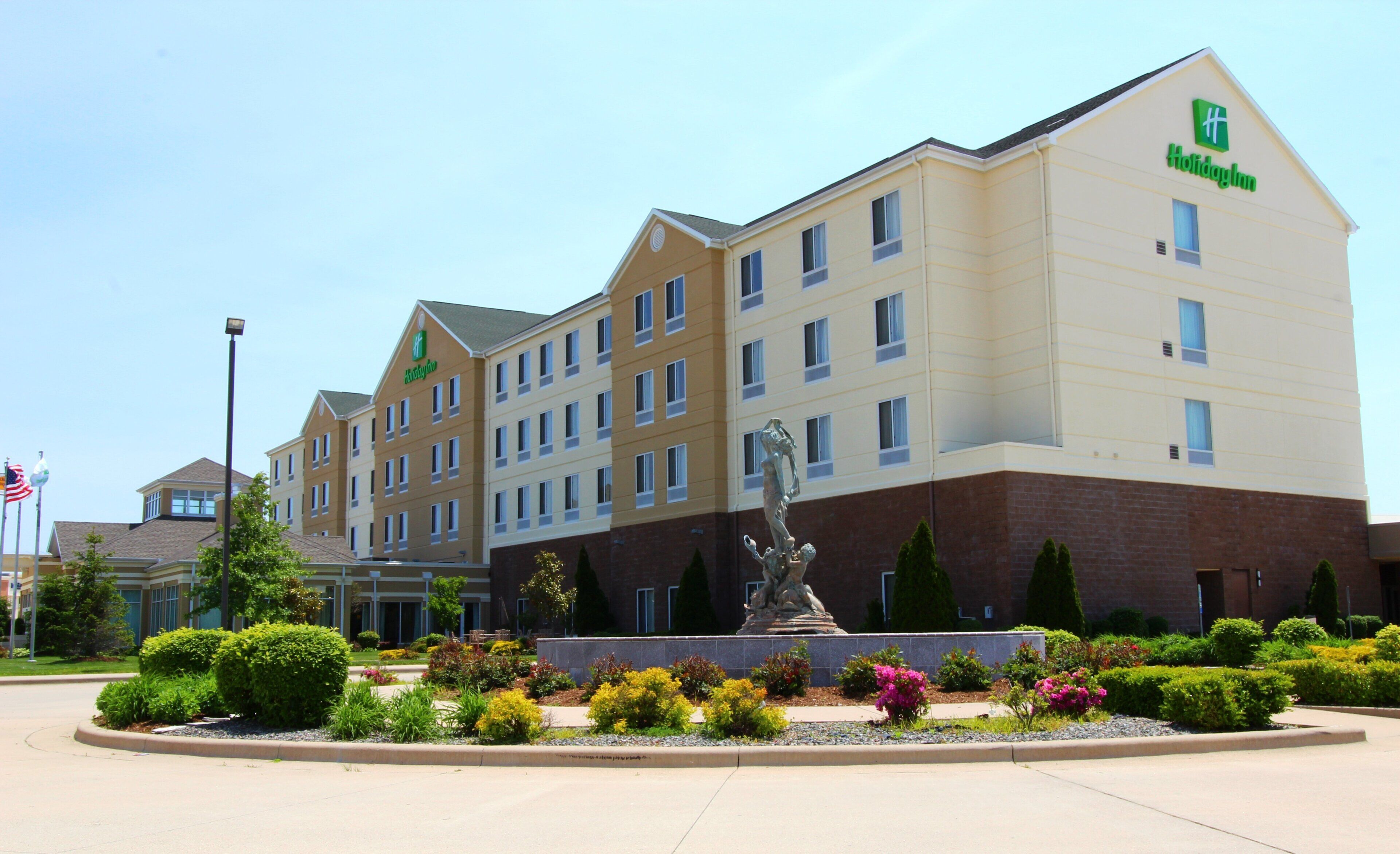 A Holiday Inn hotel with a central courtyard featuring a statue and landscaped gardens.