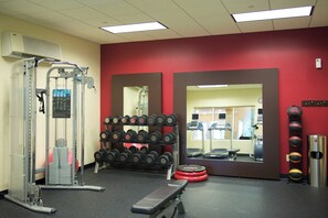 A gym with weightlifting equipment, a bench, and a mirror.