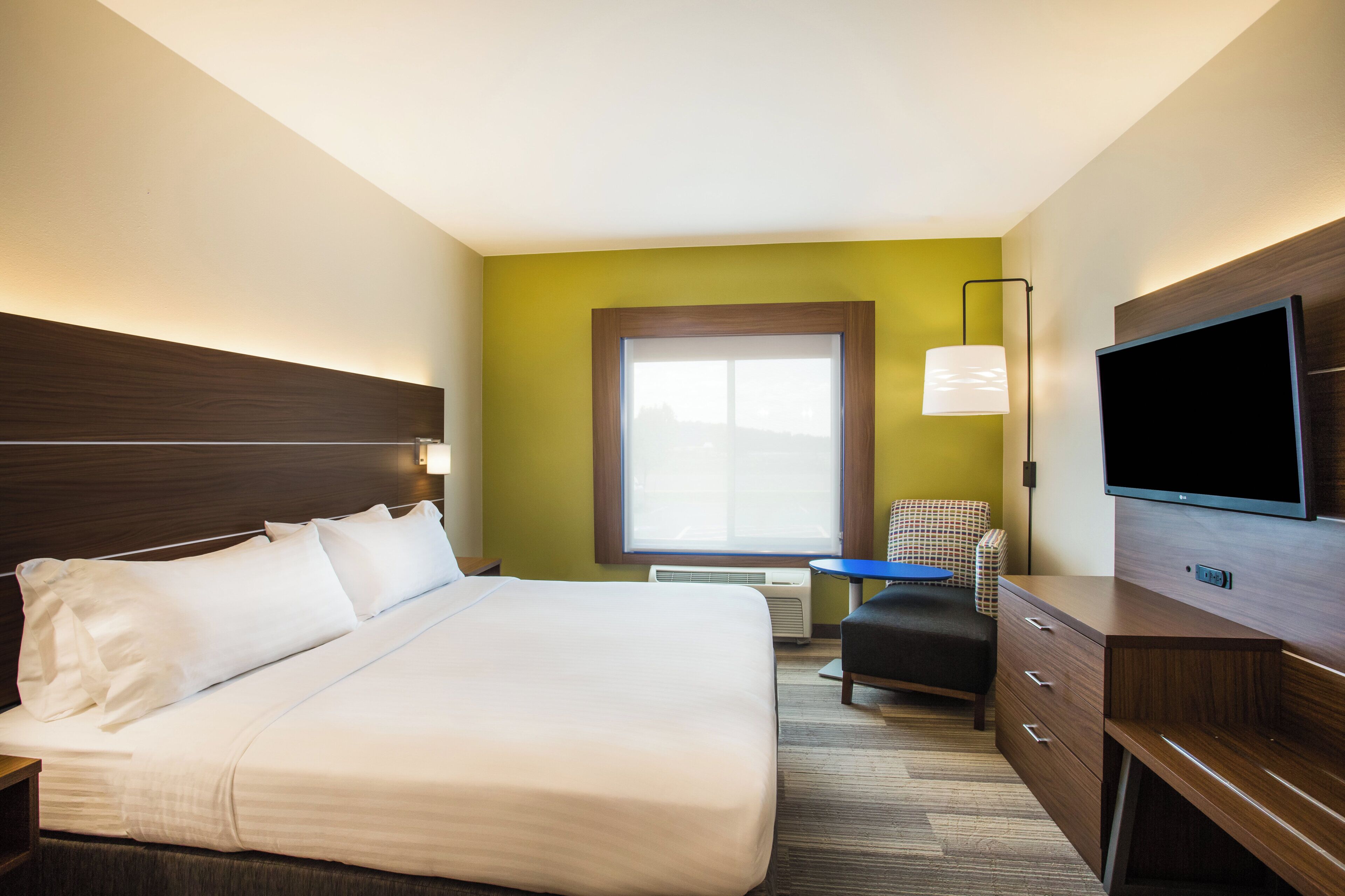 A hotel room with a large bed, a flat-screen TV, a desk, and a chair.