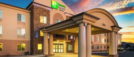 Edificio de Holiday Inn Express & Suites con fachada de piedra y entrada cubierta.