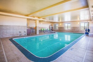 An indoor swimming pool with clear water, surrounded by tiled walls and a ceiling with exposed ductwork.
