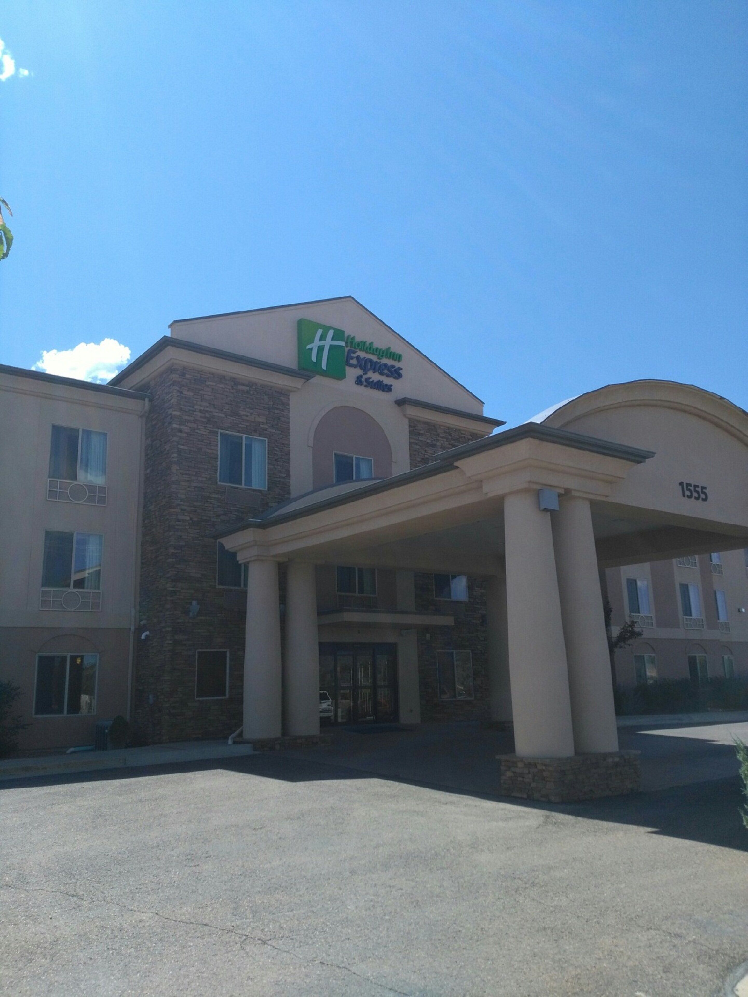A hotel with a stone facade, a green and blue sign indicating it's a Holiday Inn Express, and a number '1555' on the building.